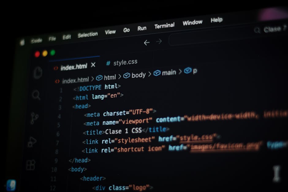 A close-up photograph of a computer screen displaying lines of HTML code in a text editor with dark background and coloured syntax highlighting. The code includes tags such as <html>, <head&g